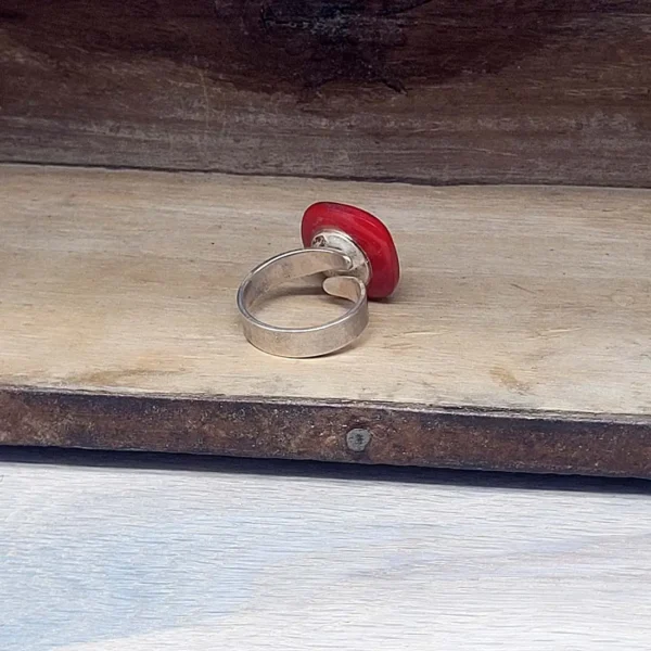 Handgefertigter Schmuck als silber Ring, offen geschmiedet, mit rotem Knopf